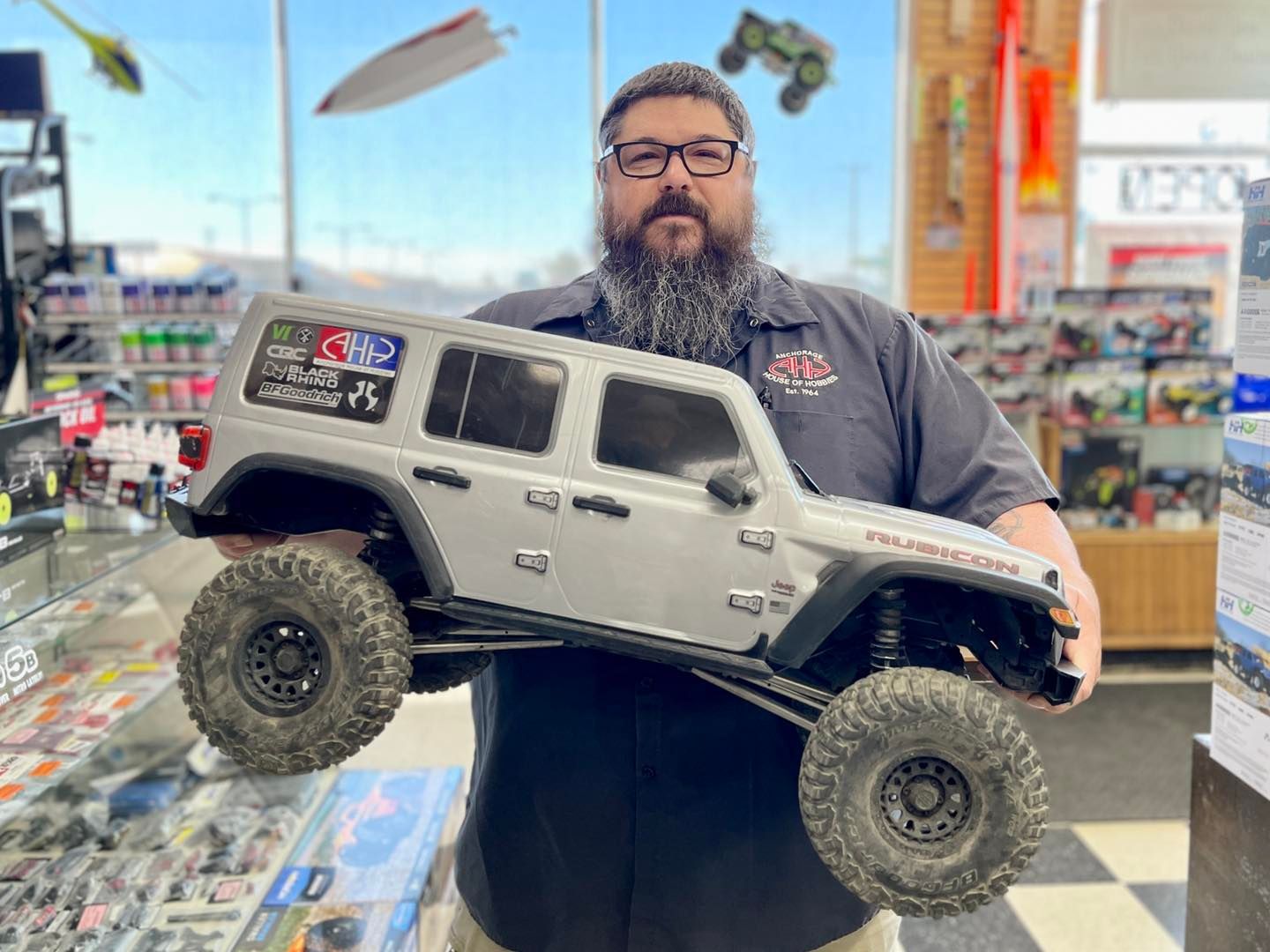 Inside the hobby shop, James shows off a large RC rock crawler, the SCX6.