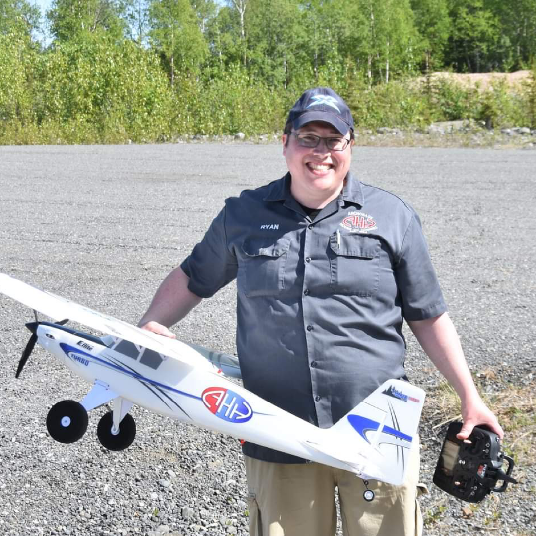 Ryan holds an RC Plane while smiling